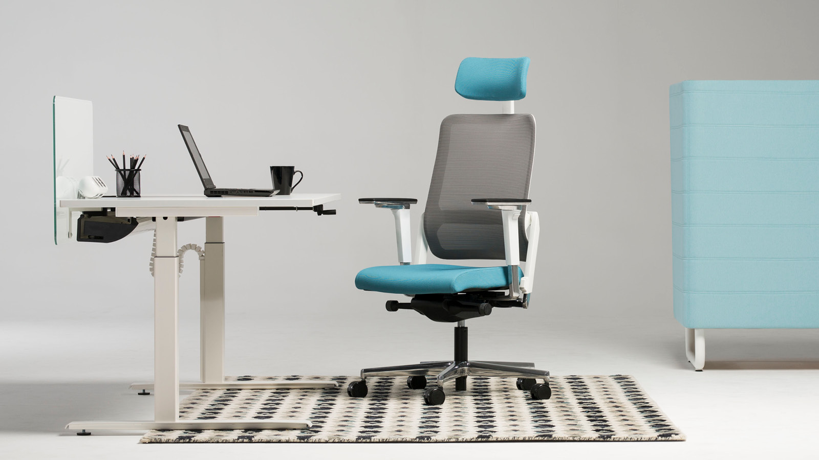 Minimalistyczne stanowisko pracy - białe biurko na stelażu metalowym wraz z niebiesko-popielatym krzesłem z podłokietnikami.